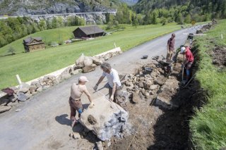 Des civilistes travaillent à la construction d'un mur de pierres sèches le long d'une route dans le Muotathal (SZ) (archives). KEYSTONE/URS FLUEELER